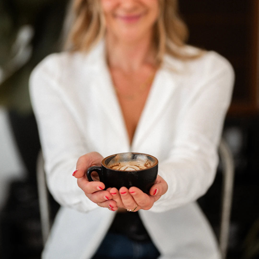 A woman holding a fresh cup of brewed Earthrise coffee alternative, smiling at the camera