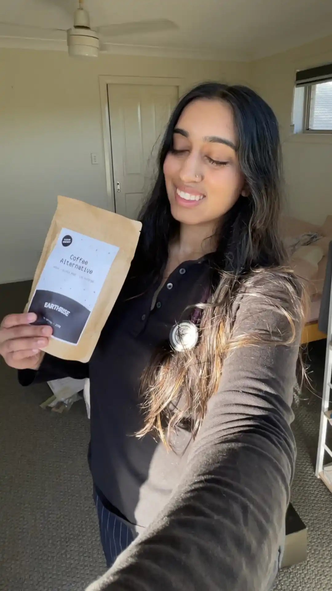 A person holding a bag of Earthrise coffee alternative, smiling with their eyes closed